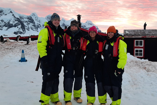 The team outside the hut in their float suits