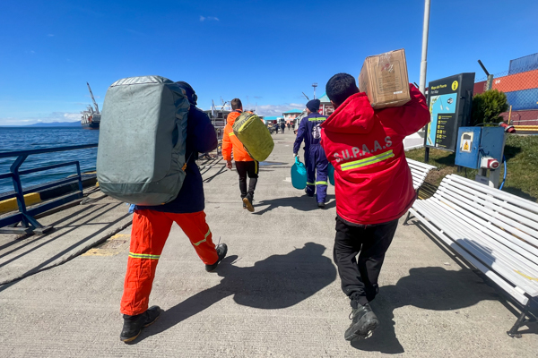 Cruise ship workers carrying luggage aboard