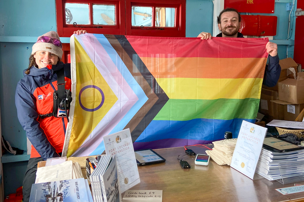 Maggie and George hold rainbow flag in shop