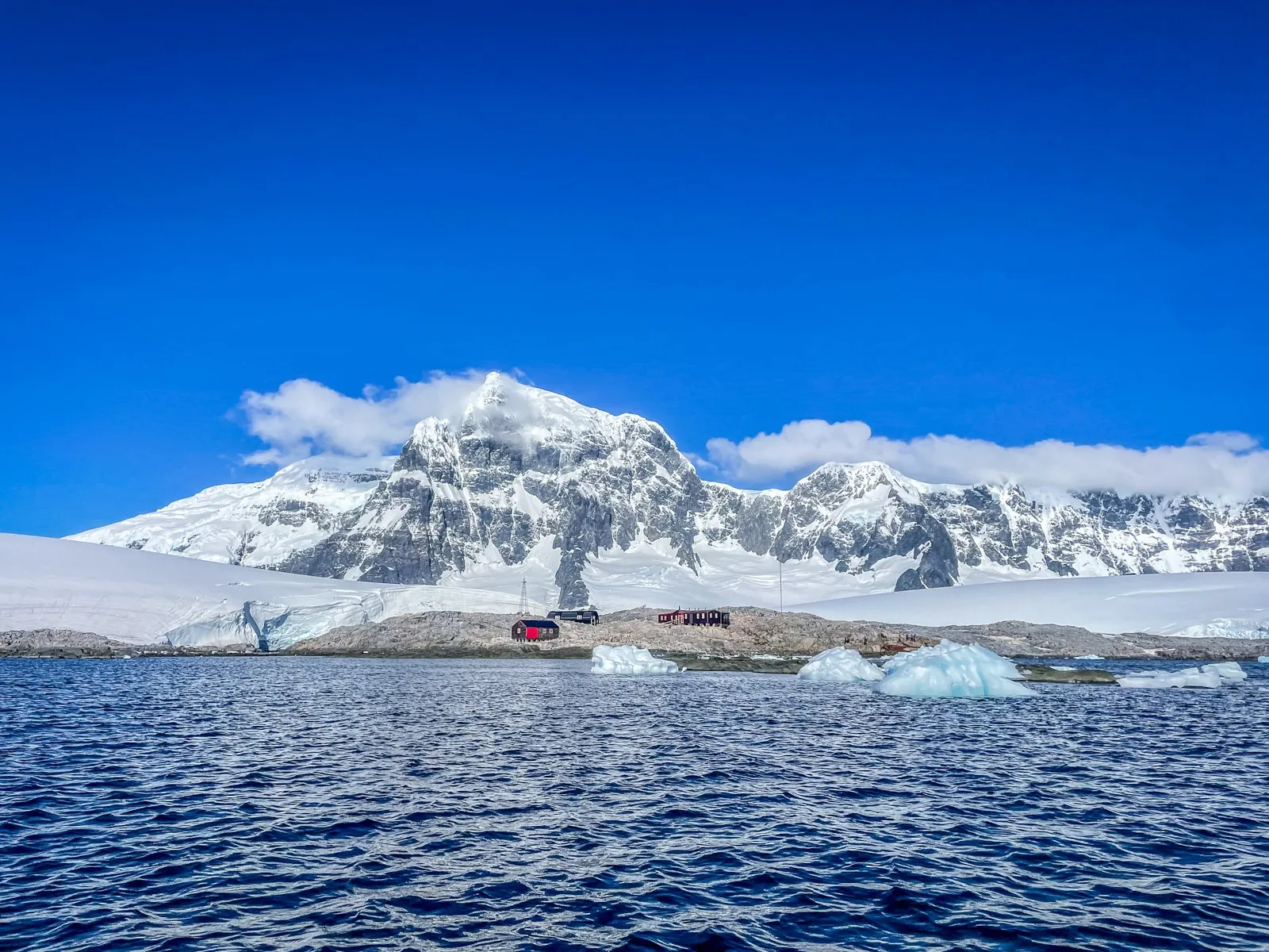 Long shot of Port Lockroy taken from a drone in Antarctica showing the mountains behind