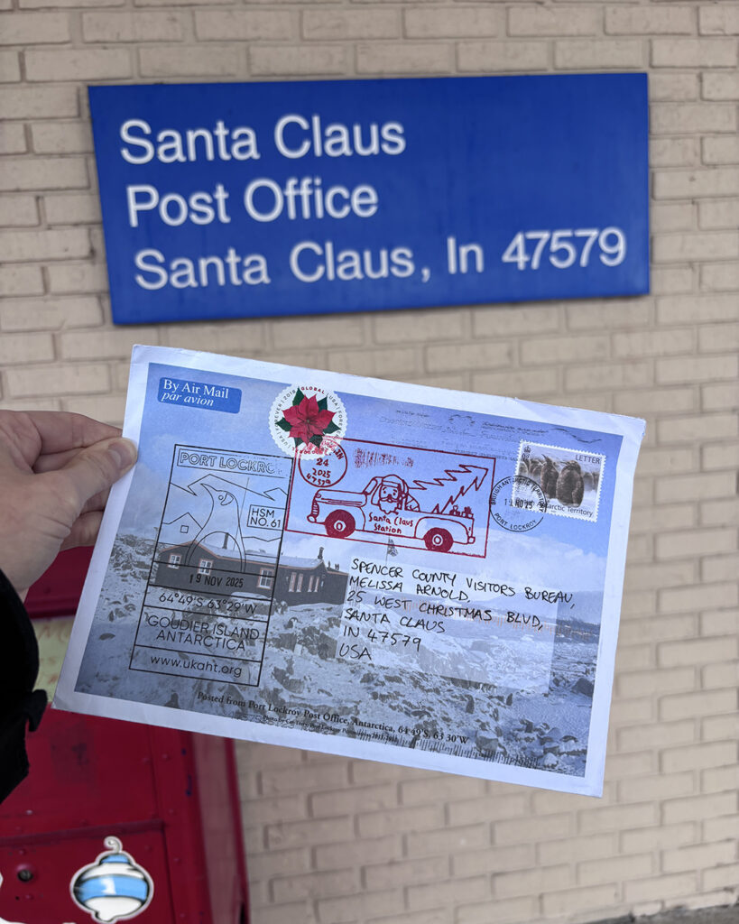 the postcard at the Santa Claus post office showing th address of the post office on a blue sign