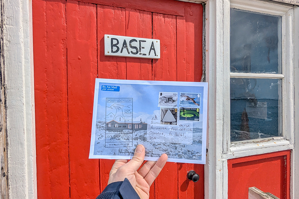 Postcard infront of red door at port lockroy